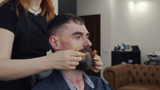 女性理发师扭曲客户胡子的切成一幅风景视频