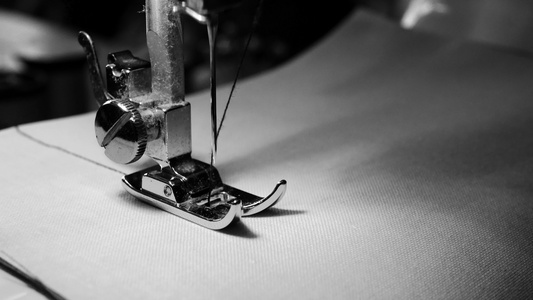 关闭白织物上的缝纫机针缓慢运动黑白色彩和黑色颜色视频
