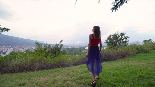 穿着红色和蓝色礼服的女孩享受着城市的风景视频