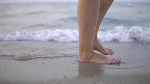 在夏日海滩上沿着海水和沙子的潮流行走的年轻女子紧紧12秒视频