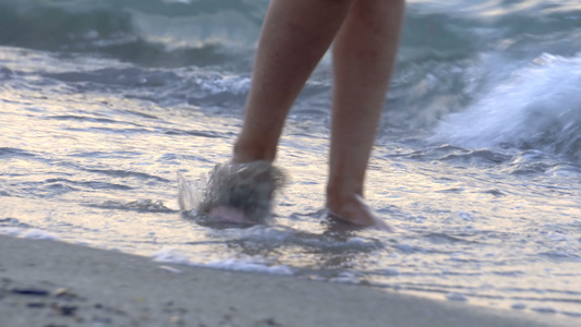 在夏日海滩上沿着海水和沙子的潮流行走的年轻女子紧紧视频