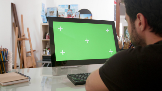留胡子的男子看着电脑上的绿色屏幕视频
