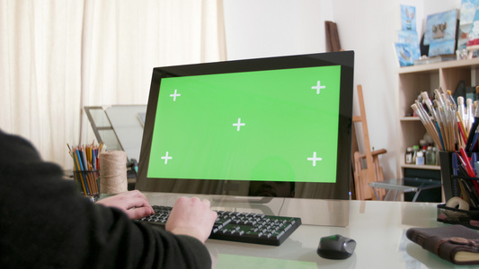 一个用绿色屏幕在电脑上工作的人的缓慢拍摄镜头视频