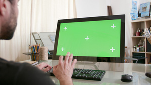 年轻的艺术家在他的电脑上工作显示屏上有绿屏11秒视频
