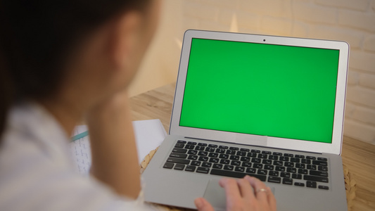 绿色的电脑屏幕女孩坐在桌旁远程学习工作上网冲浪穿着视频