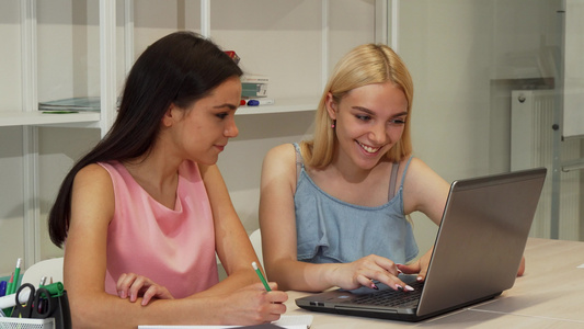 两名美丽的女学生一起使用笔记本电脑学习视频