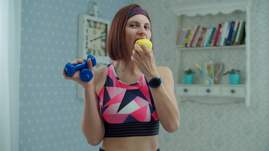 30多岁的年轻女子穿着运动服戴着哑铃手里拿着苹果水果视频