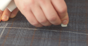 男子用粉笔在织物上绘制自制的西装图案20秒视频