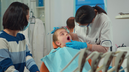 带面罩的儿科牙医为小女病人治疗牙齿视频