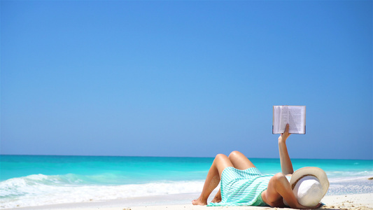 热带白沙滩期间年轻女子阅读书读物视频
