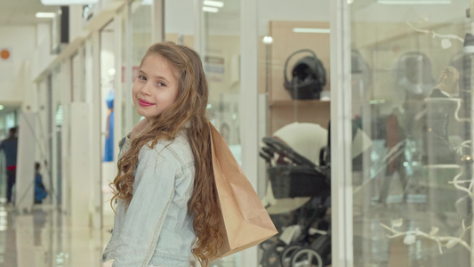快乐的小女孩笑着对着镜头微笑在商场拿着购物袋视频