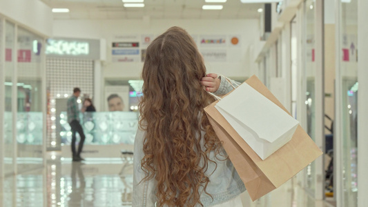一个卷发小女孩在商场看服装店时被一头卷发的小姑娘拍到视频