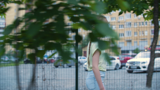 在现代城市的住宅区行走的两条辫子的少女年轻的少女在视频
