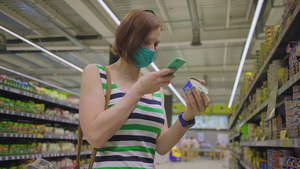 带着口罩的女性在手机的帮助下查看罐子信息10秒视频