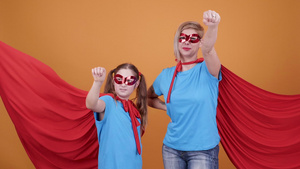 一个年轻女孩和一个女人当着橙色背景的面成为超级英雄31秒视频