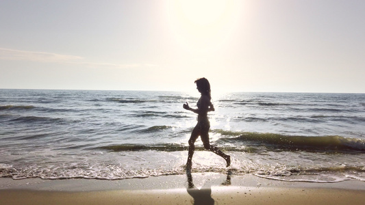 穿着比基尼的快乐美丽的双影女孩在日落时在海滩上奔跑视频