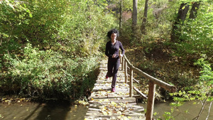 美丽的年轻女子在木桥上森林公园里跑来跑去8秒视频