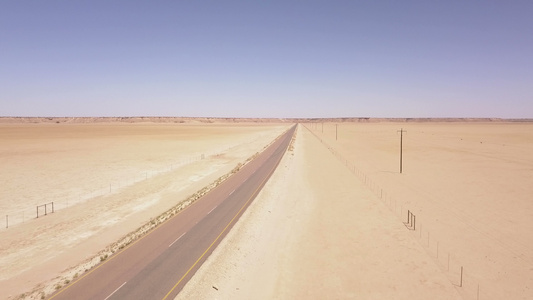 穿越沙漠地貌的长长道路的空中飞行视频