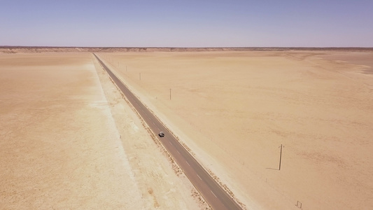 穿越沙漠地貌的长长道路的空中飞行视频