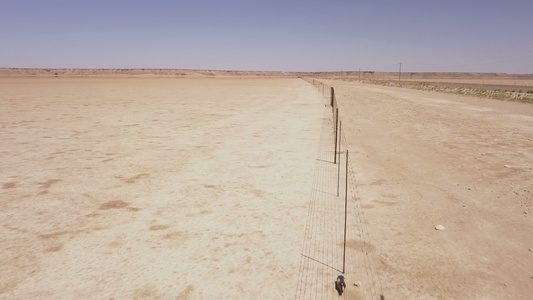 穿越沙漠景观的长长栅栏的空中飞行视频