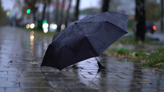 在雨季有人在路上投掷黑色雨伞视频