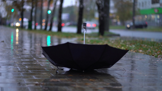 在雨季有人在路上投掷黑色雨伞视频