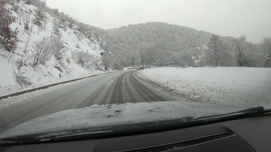 在冬季积雪的雪雪中驾驶车在雪覆盖的雪山路上行驶驱动视频