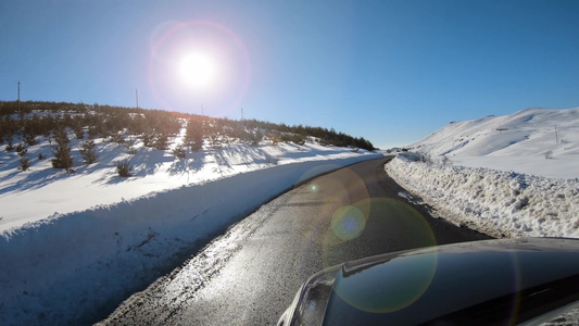 第一视角驾驶一辆汽车穿过农村山路上的雪上面有太阳耀斑视频