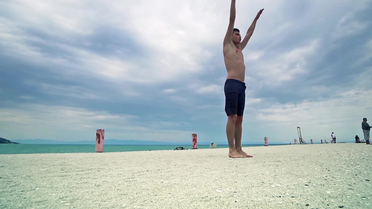 坐在海滩上跳高的Parkour男人的全身肖像进行后视频