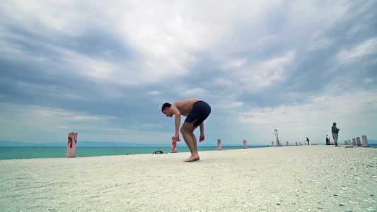 在海滩上跳高背翻转的Parkour男人全身肖像视频