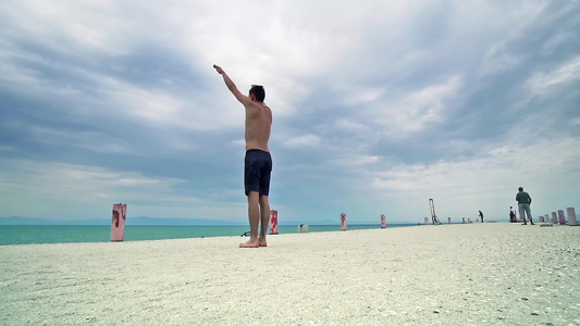 坐在海滩上跳高的Parkour男人的全身肖像进行后视频