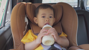 男孩子在车里的座椅上喝着瓶装牛奶31秒视频