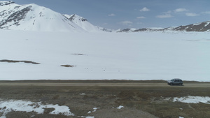 SUV车在阳光明媚的白天在雪山高海拔的沙砾路上行驶28秒视频