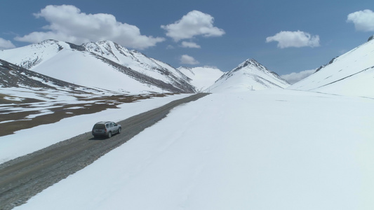 SUV车在阳光明媚的日落雪山上走碎石路空中观察无人机视频