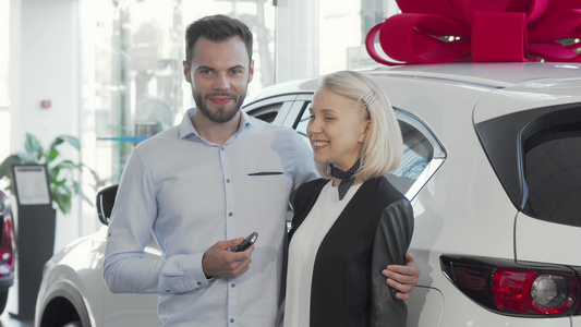 幸福的一对年轻夫妇站在他们的新车旁边在经销店视频