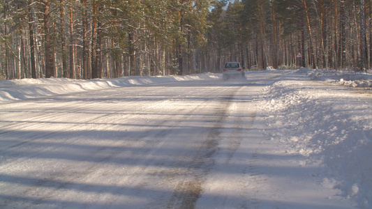 在阳光明媚的白天穿过冬季森林驾车在雪地高速公路上行驶视频