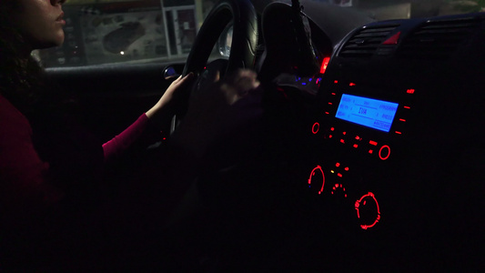 晚上开车—漂亮的年轻女人晚上在城市里开着现代汽车视频