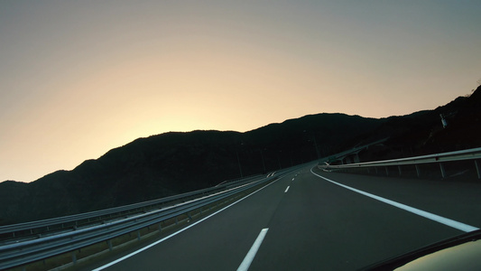 在空沥青高速公路路和日落的天空反呼号上行驶视频
