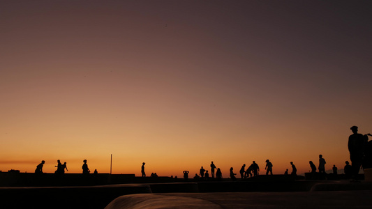 年轻的跳跃滑板手骑长板夏季日落背景的剪影加利福尼亚州视频