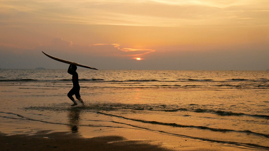 年轻快乐冲浪男子在日落时分在热带海滩上用长冲浪板奔跑视频