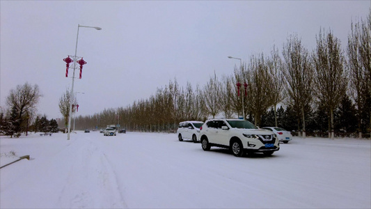 4k实拍北方飘雪的冬季街道上缓慢行驶的汽车视频