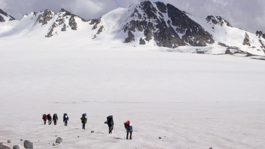 一群山上登山者背着背包使用头盔抽筋绳子和冰斧在冰川视频