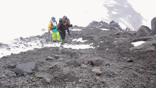 一群背负着背包的登山者在山上走在石块上他们用远足杆视频