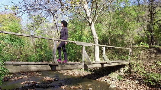 女运动员在森林中徒步穿越木桥Stadicam漫步拍摄视频