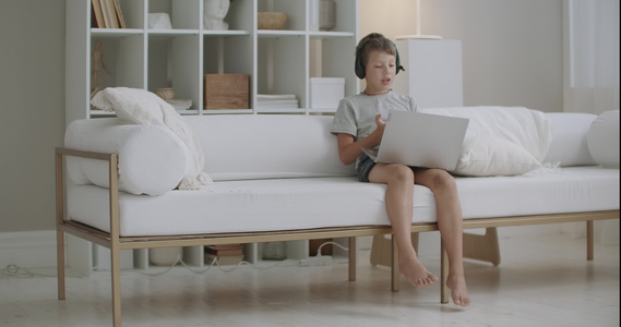 小学生在白天独自呆在家里在网上聊天使用笔记本和耳机视频