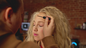 给长头发的年轻女孩化妆的发型设计师8秒视频