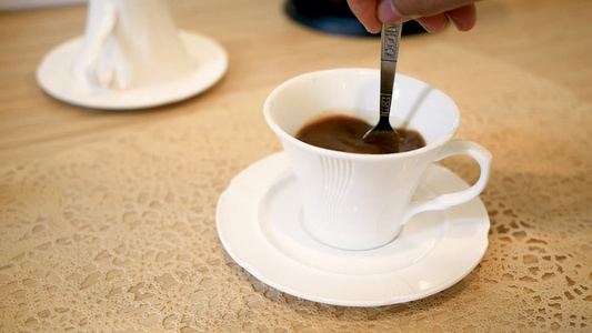 在桌子上一个白色的杯子里用勺子来搅拌咖啡视频