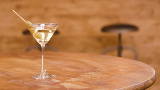 一杯马提尼酒在木制桌上加橄榄视频
