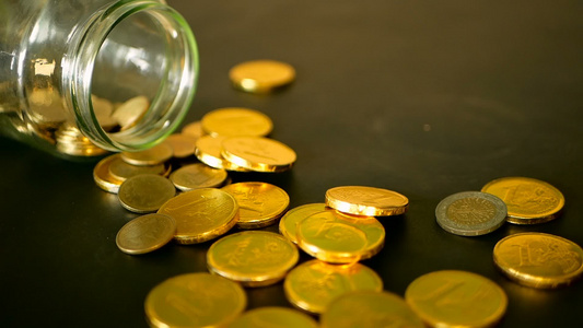 黑桌上的金币和旋转便士黄色硬币从罐子上掉下来了视频