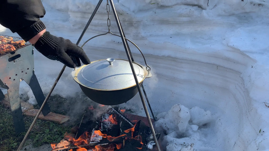 一个旅游锅在冬天挂在篝火上冬天在大自然的火上做饭男人视频